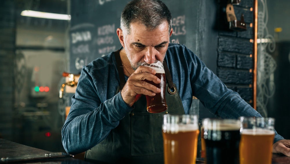 A brewer tasting craft beer in a brewery, evaluating different types of beer in glasses.