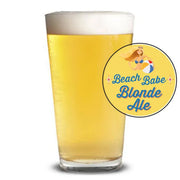 Glass of blonde ale with 'Beach Babe Blonde Ale' label on a white background