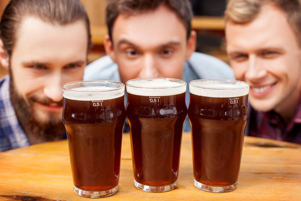 A homebrewing setup with fermenter, hops, malt, and beer, featuring a smiling beardless brewer breaking brewing myths.